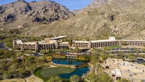 A large hotel with multiple buildings, a golf course, and a swimming pool.