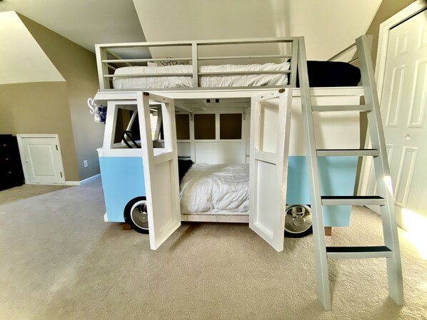 A bunk bed room with a built-in desk and ladder.