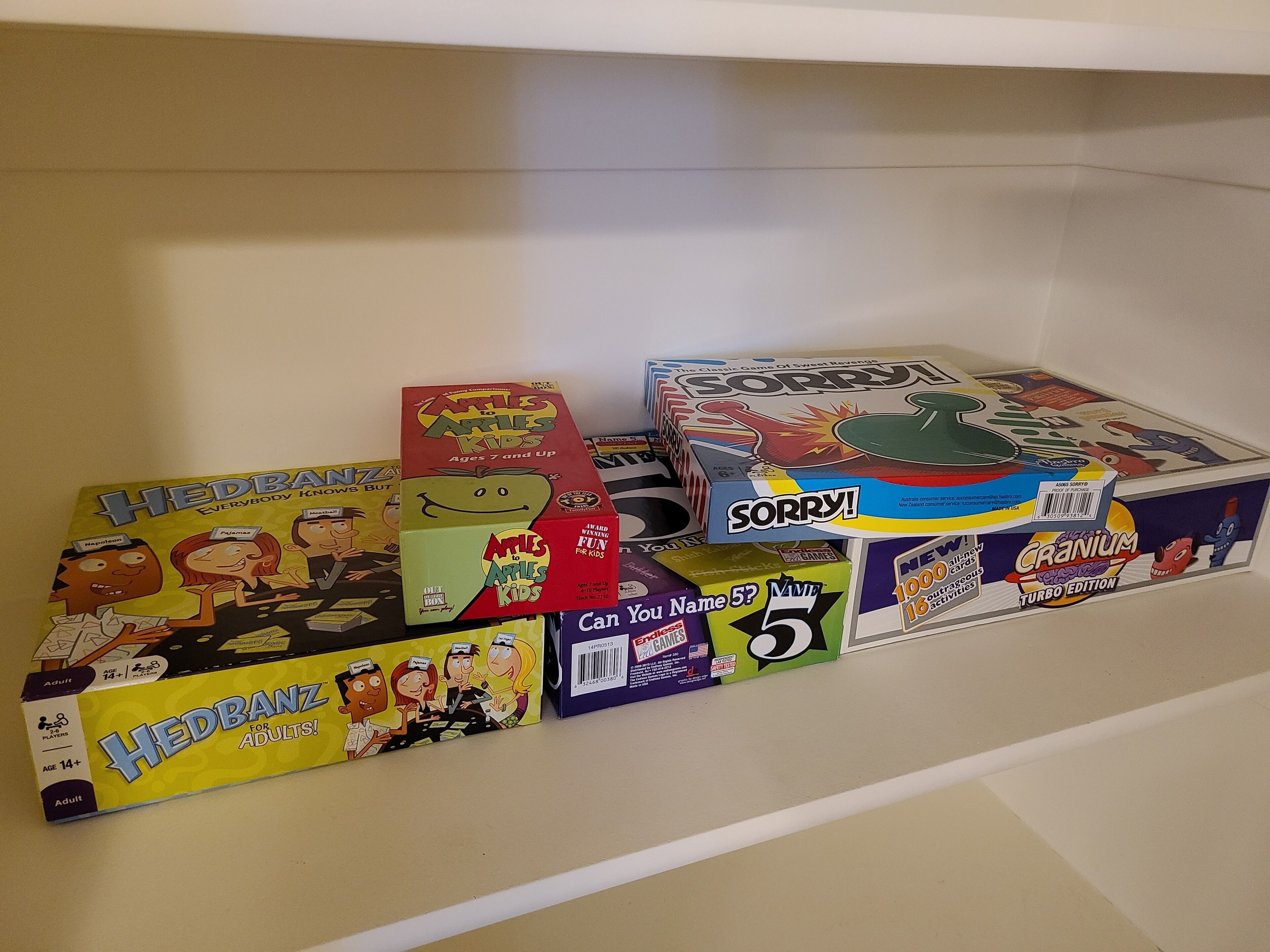A shelf with various board games, including 'Apples to Apples Kids' and 'Sorry!'.