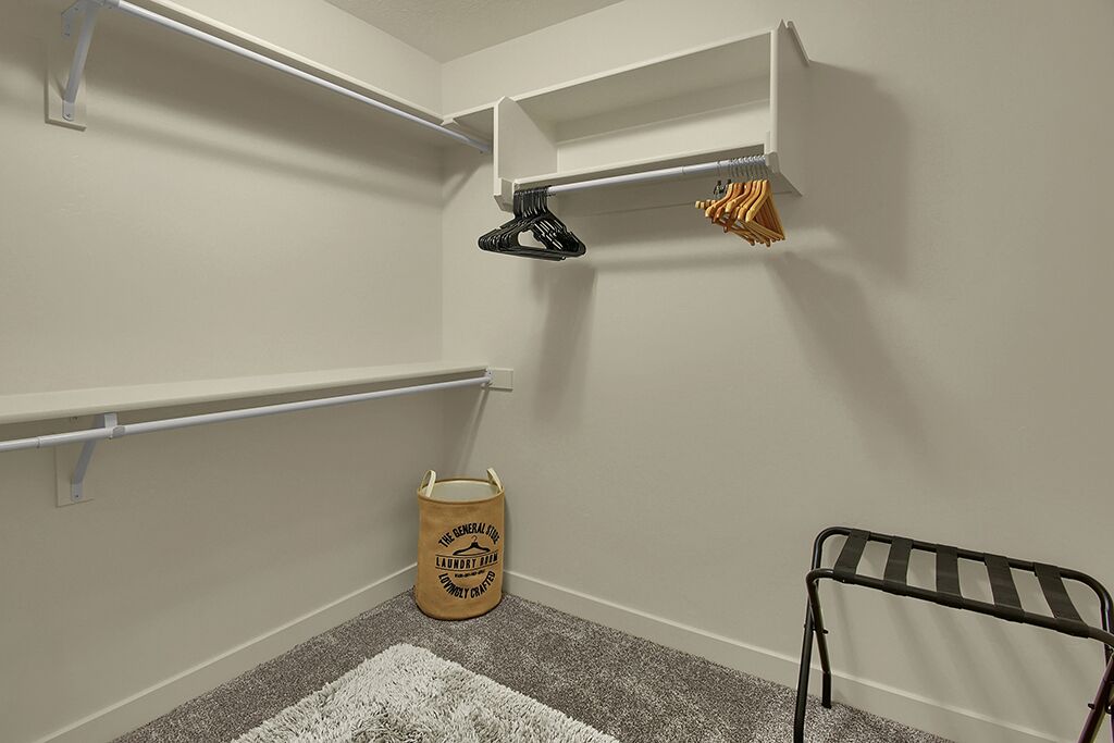 Un cuarto de lavandería con estantes, un tendedero y una cesta de ropa.