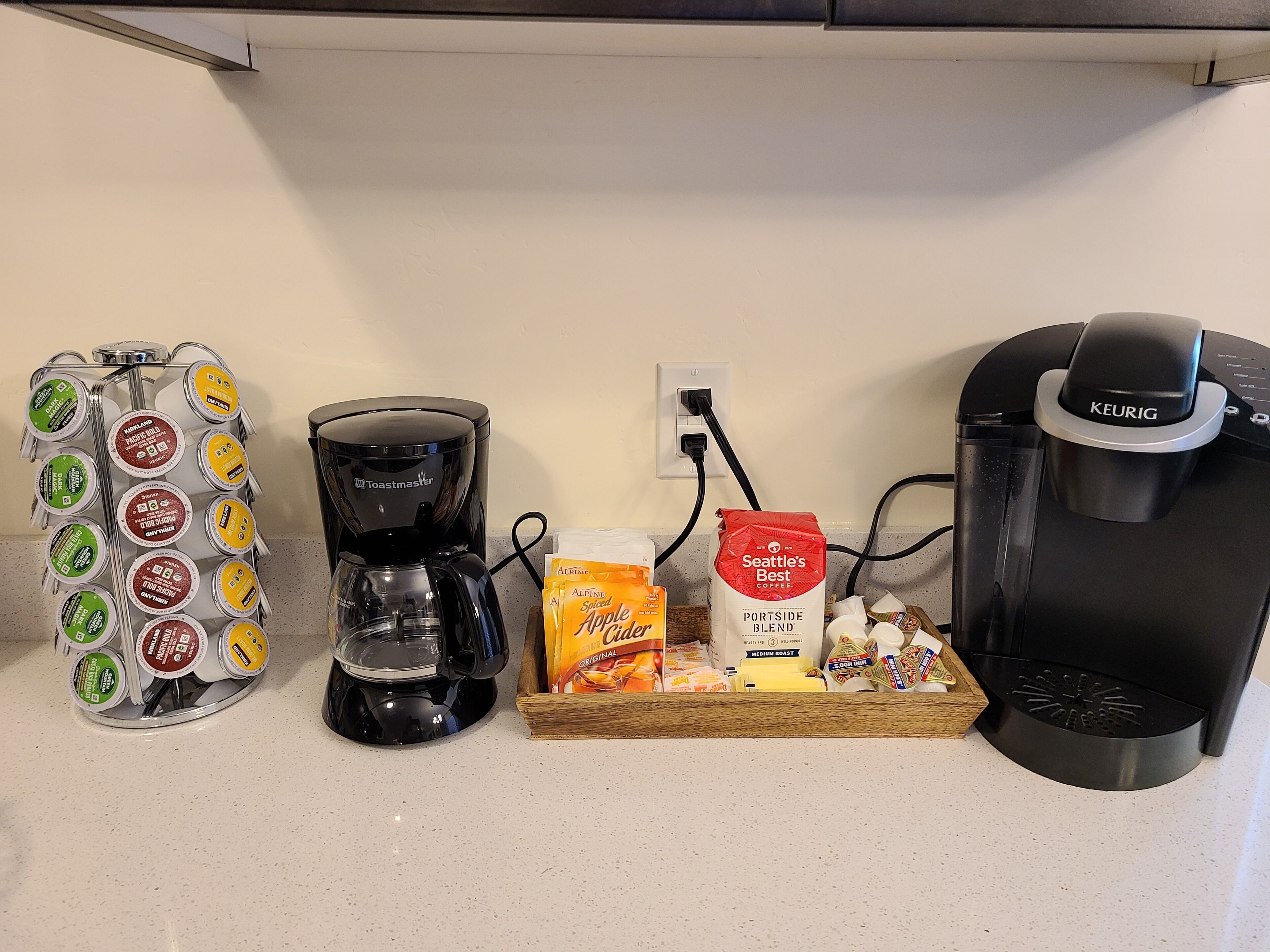 A coffee station with a Keurig, a Toastmaster coffee maker, and a Keurig branded coffee maker.