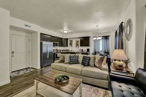 Ein modernes Wohnzimmer mit einer Couch, einem Couchtisch und einem Essbereich inklusive Kühlschrank und Mikrowelle.