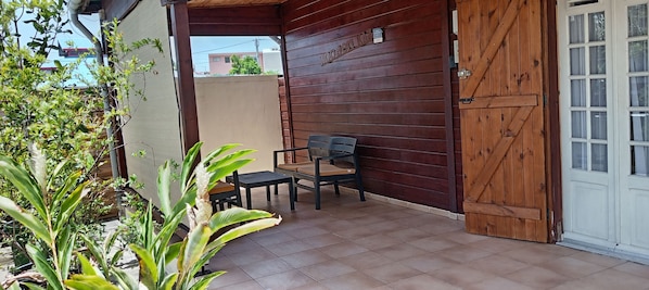 A wooden door with a sign, a bench, and a small table in a covered outdoor area.
