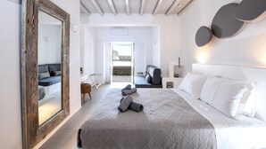 A modern bedroom with a large bed, a mirror, and a view of a balcony.