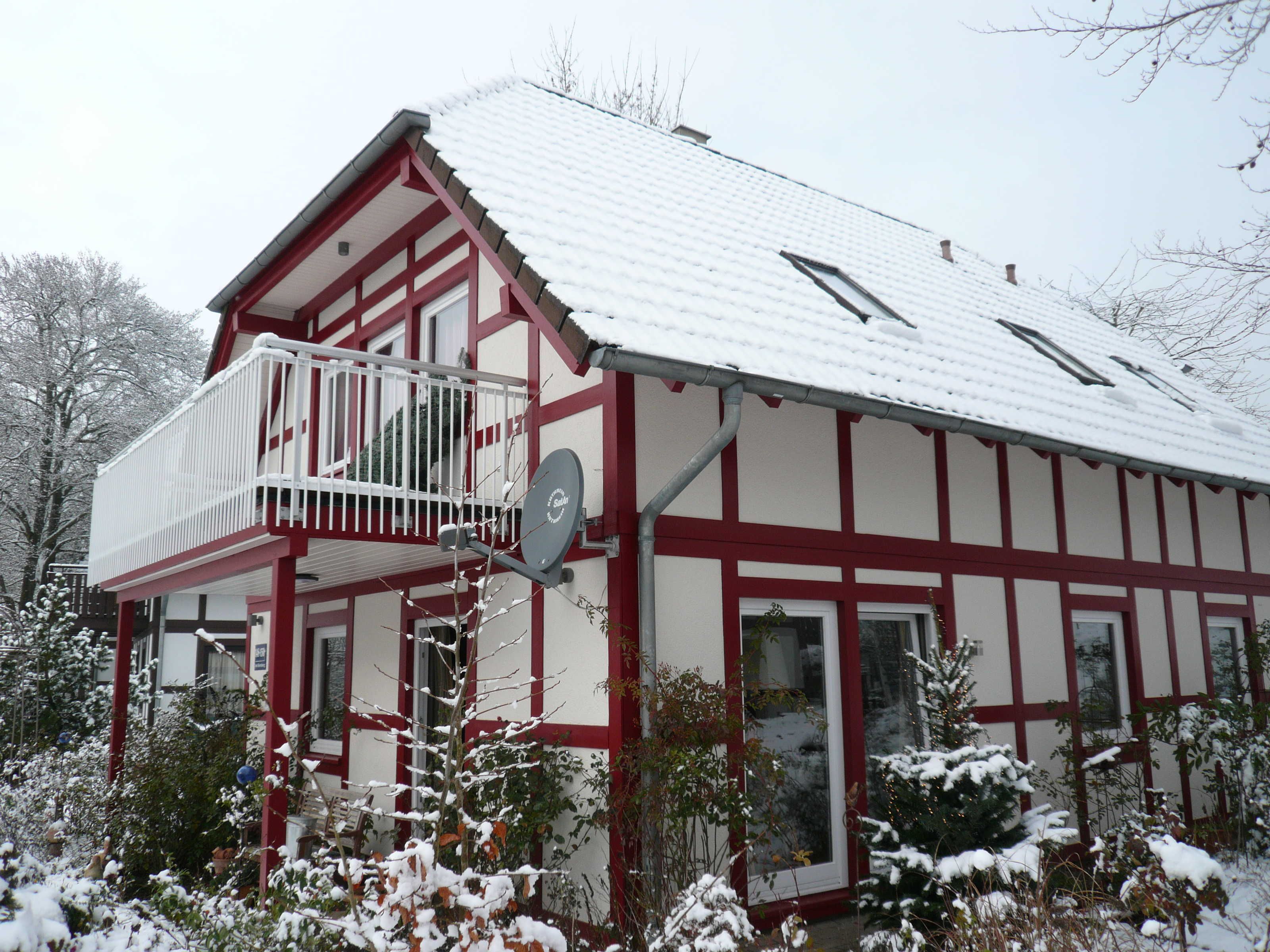 A two-story building with a balcony, a satellite dish, and a red and white exterior.