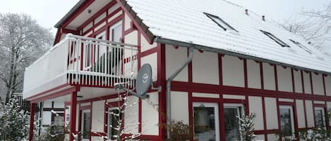A two-story building with a balcony, a satellite dish, and a red and white exterior.