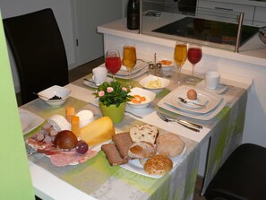 Une table de petit-déjeuner avec divers aliments, des boissons et une petite plante en pot.