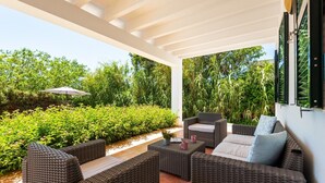 An outdoor patio with wicker furniture, a small table, and a potted plant. - Villa Rose. Private swimming pool. Free AC & Wifi (Sant Lluís)