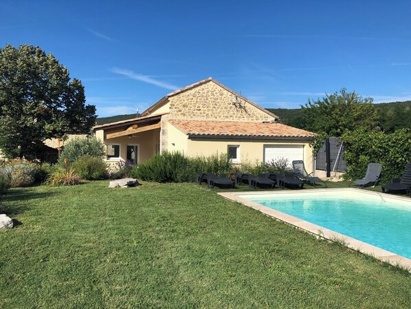 A house with a swimming pool, a covered patio, and a stone facade.