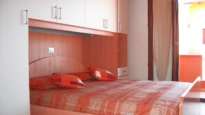 Una camera da letto con un letto, armadi a muro e una porta scorrevole in vetro che dà sull'esterno.