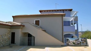 A multi-story building with a tiled roof, a staircase leading to the upper floor, and a gated entrance. - Apartment Sleeps 4 With Free Parking (Badesi)