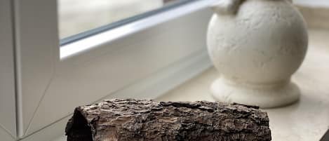 Un rebord de fenêtre orné d’une bûche de bois et d’une statue blanche.