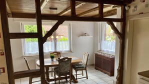 Ein Essbereich mit Holztisch und -stühlen, einem Schrank und einem Fenster mit Blick auf Grünflächen.