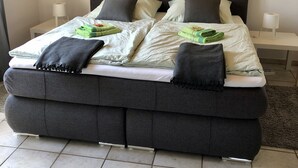 Ein Doppelbett mit dunklem Kopfteil, zwei Nachttische und zwei an der Wand befestigte Blumenbilder.