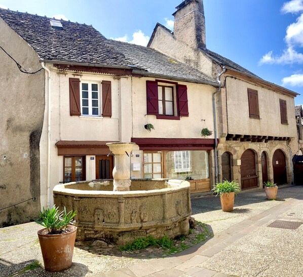 A historic building with a courtyard, a fountain, and potted plants.