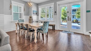A dining area with a wooden table and chairs, a chandelier, and large windows with blinds. - 🐙Golf Cart + Bikes Included-Pools-2 Masters-Octopus's Garden🐙 (Santa Rosa Beach)