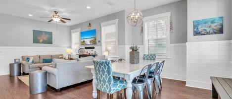 A spacious living area with a dining table, chairs, and a sofa.