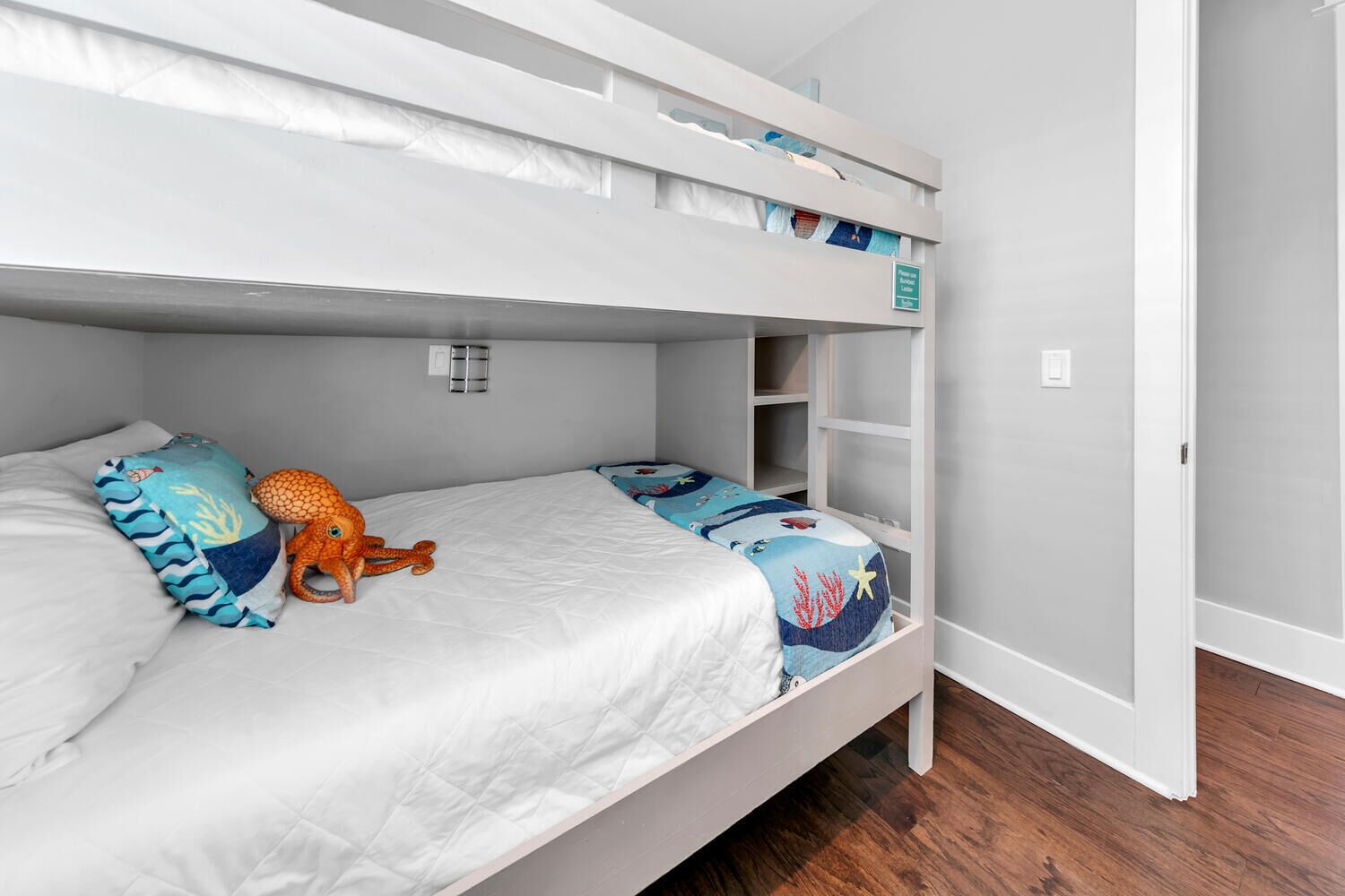 A bunk bed with a white mattress and a plush octopus toy.