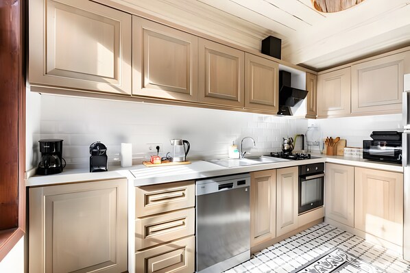 A modern kitchen with light wood cabinets, stainless steel appliances, and a tiled backsplash.