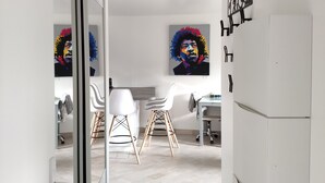 A modern kitchen with white cabinetry, a refrigerator, and two chairs. There are two paintings on the wall, and a ceiling light fixture is visible. - Modern 4-star 2-bedroom apartment in the center of Aix with parking and terrace (Aix-en-Provence)