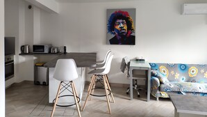 A modern kitchen with a dining area, a sofa, and a colorful artwork on the wall. - Modern 4-star 2-bedroom apartment in the center of Aix with parking and terrace (Aix-en-Provence)