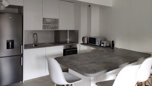 A modern kitchen with a central island, white cabinets, stainless steel appliances, and a built-in microwave. - Modern 4-star 2-bedroom apartment in the center of Aix with parking and terrace (Aix-en-Provence)