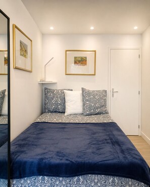 A bedroom with a bed, a door, and two framed pictures on the wall.