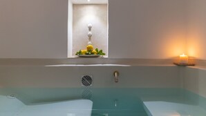 A modern bathroom with a glass-enclosed bathtub, a wall-mounted sink, and a small window with a decorative plant.