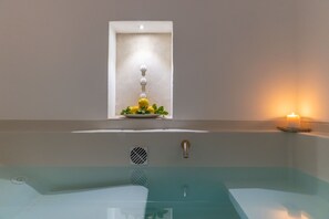Une salle de bain moderne avec une baignoire entourée de parois en verre, un lavabo fixé au mur et une petite fenêtre agrémentée d’une plante décorative.