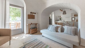 A modern living room with a white sofa, a striped rug, and a wooden table with a basket.
