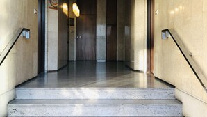 Et moderne interiør med en marmortrappe, der fører op til en elevator.