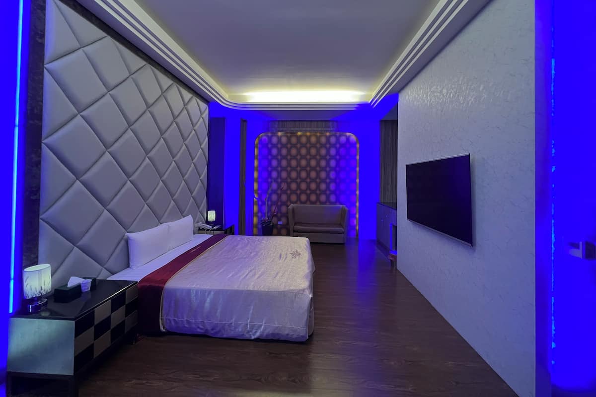 Ein modernes Hotelzimmer mit einem großen Bett, einem an der Wand montierten Fernseher und einer Sitzecke mit einer Couch.