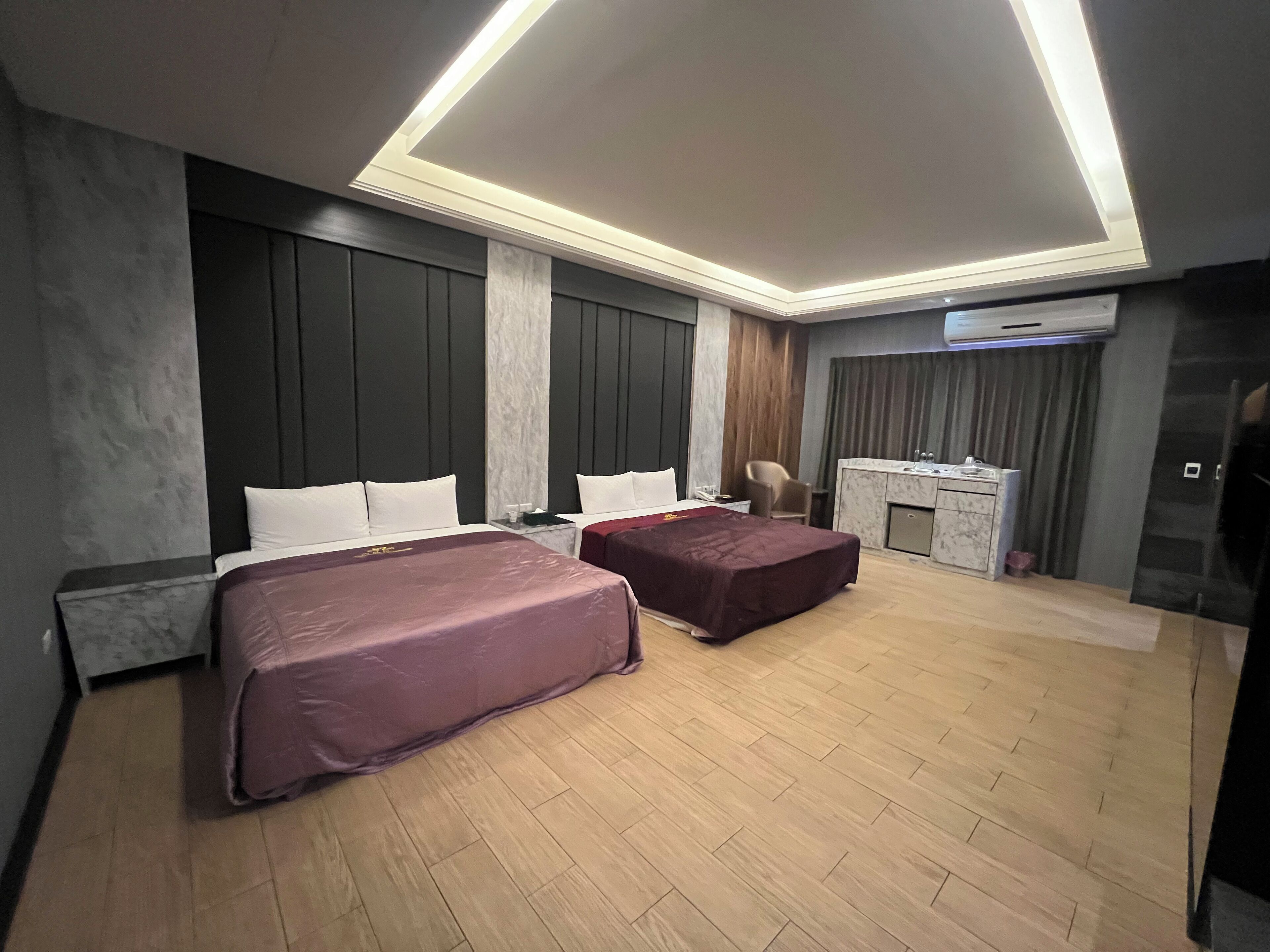 A modern hotel room with two beds, a desk, and a minibar.