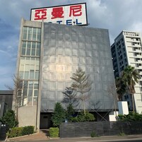 Un edificio moderno de hotel con un letrero grande que muestra el nombre en letras rojas y azules.