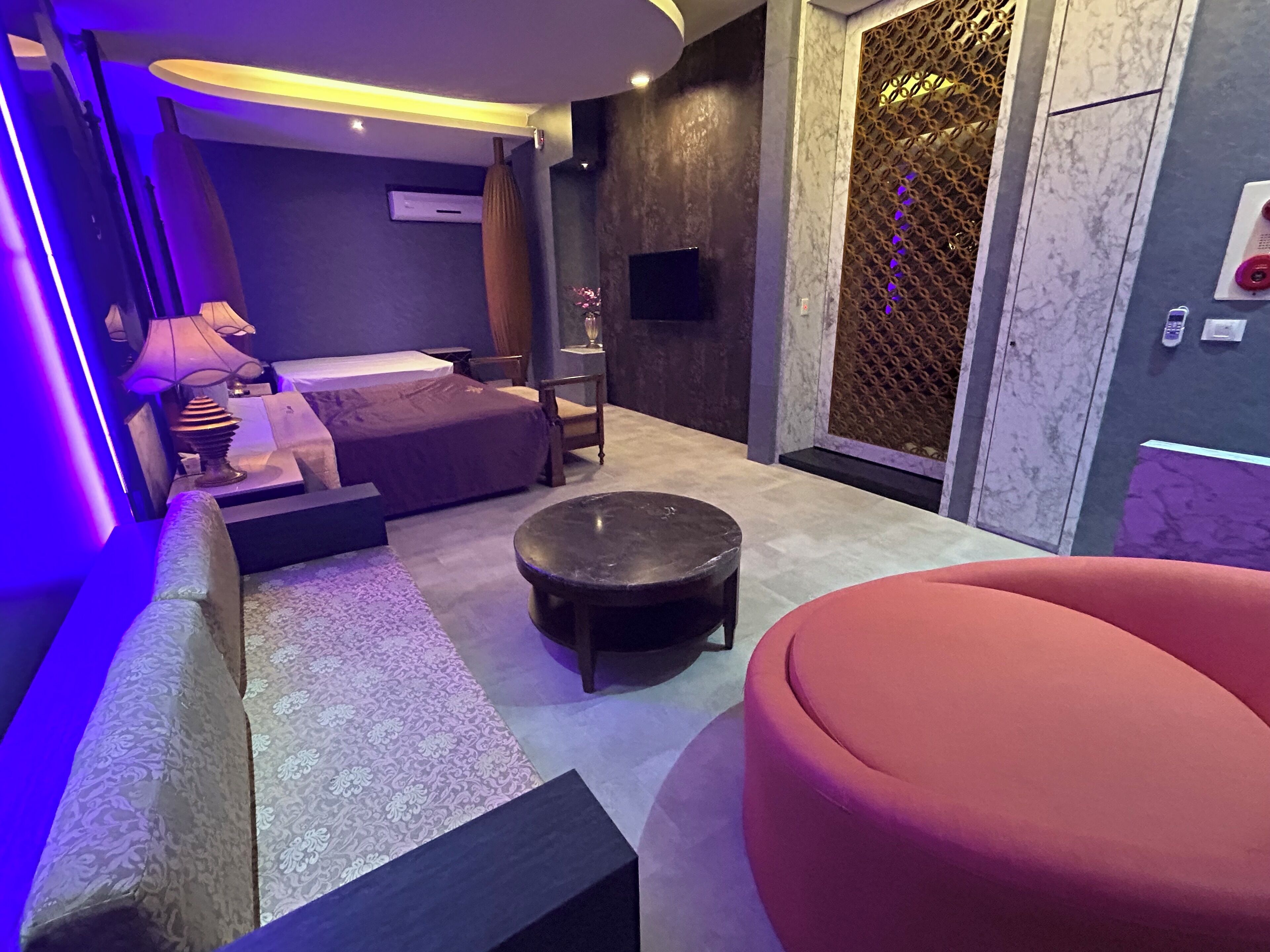 Una habitación de hotel moderna con una cama, una mesita, un sofá y una silla roja.