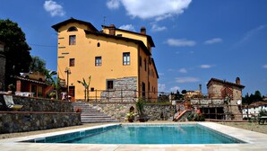 A two-story building with a stone staircase leading to a pool area. - Libeccio studio apartment with panoramic view of the hills (Toscana)