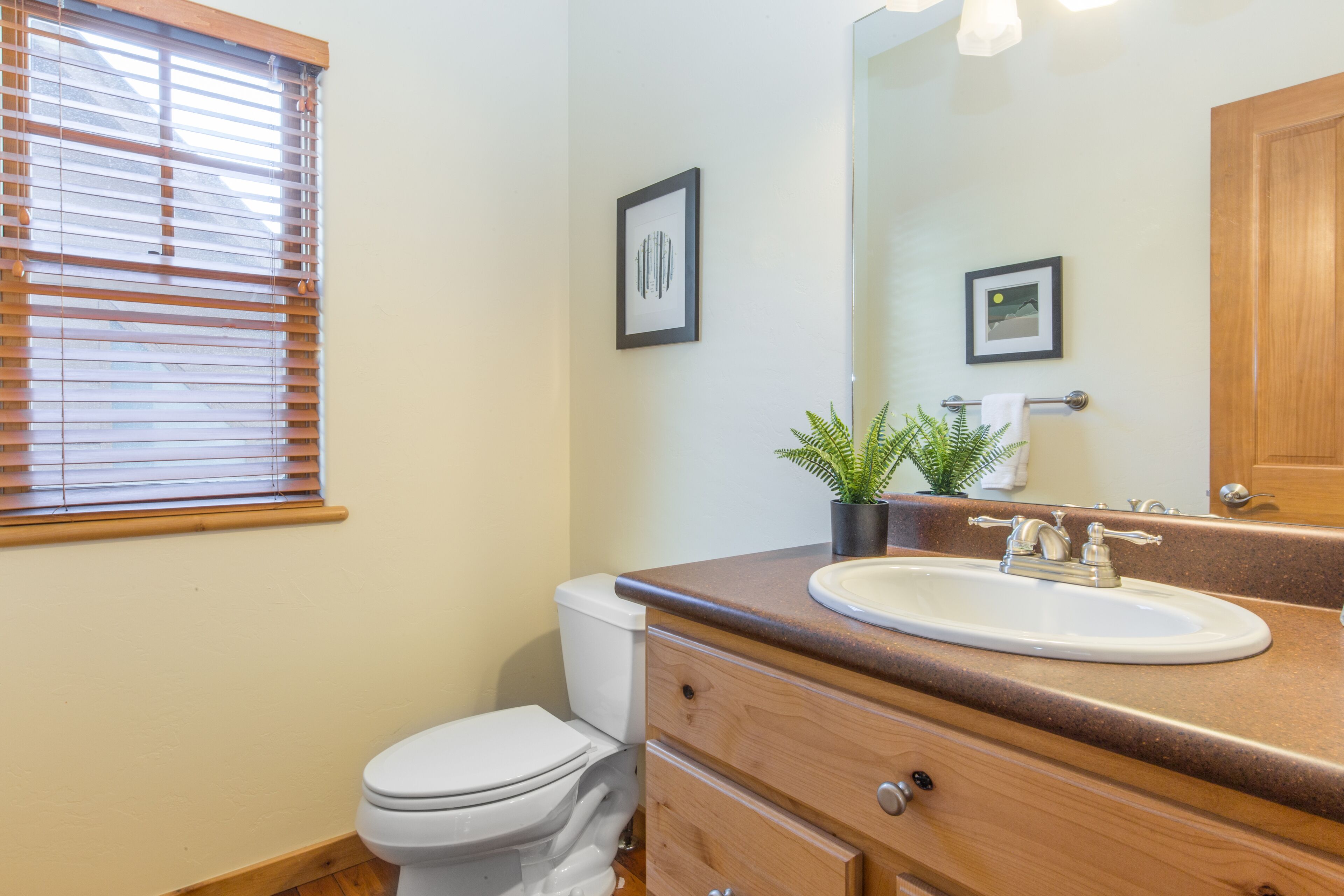 A bathroom with a toilet, sink, vanity, and a mirror.