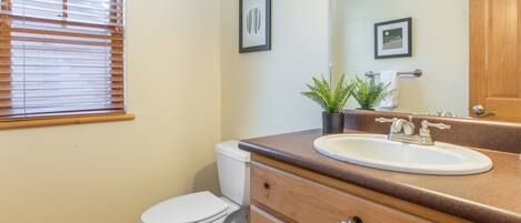 A bathroom with a toilet, sink, vanity, and a mirror.