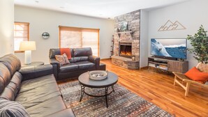 Una sala de estar con chimenea, un sofá, un televisor y una mesa de centro.