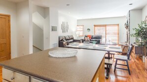 Una cocina moderna con encimera de granito, un comedor con mesa y sillas, y una sala de estar con sofá y mesa de centro.