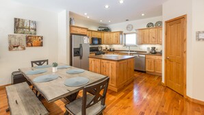 Una cocina amplia con armarios de madera, una isla central y un comedor con mesa y bancos de madera.