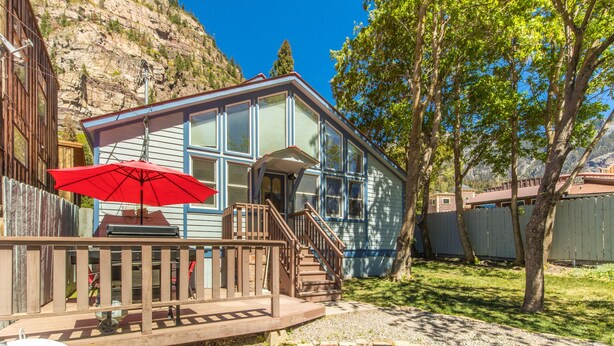 A house with a deck, a red umbrella, and a view of a mountain. - Cozy Downtown Pet Friendly Home with Fiber Internet! Fenced Outdoor Area! (Ouray)
