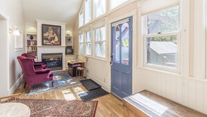 A cozy living room with a fireplace, a blue door, and large windows. - Cozy Downtown Pet Friendly Home with Fiber Internet! Fenced Outdoor Area! (Ouray)