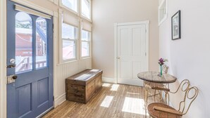 A room with a blue door, a wooden bench, a white door, a small round table with a vase, and a chair. - Cozy Downtown Pet Friendly Home with Fiber Internet! Fenced Outdoor Area! (Ouray)