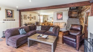 Un salón acogedor con un sofá de cuero marrón, una mesa de centro de madera y un sillón de cuero.