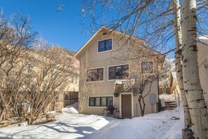 Une maison à deux étages avec une porte d’entrée, un garage et une allée recouverte de neige.