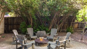 Un patio con sillas Adirondack dispuestas alrededor de un brasero.