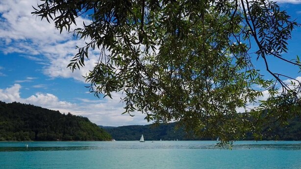A calm lake with a clear sky, surrounded by hills and trees. - BETWEEN LAKES AND MOUNTAINS - DETACHED HOUSE AIR-CONDITIONED 3-BEDROOM WITH ENCLOSED GROUNDS (Barésia-sur-l'Ain)