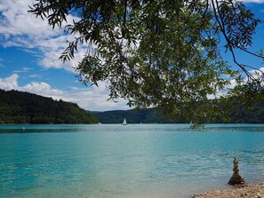 A calm lake with a clear sky, surrounded by hills and trees.