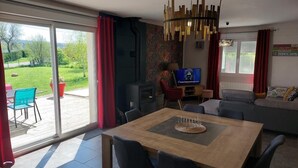 A modern living room with a dining area, large sliding glass doors to a patio, and a TV in the background. - BETWEEN LAKES AND MOUNTAINS - DETACHED HOUSE AIR-CONDITIONED 3-BEDROOM WITH ENCLOSED GROUNDS (Barésia-sur-l'Ain)